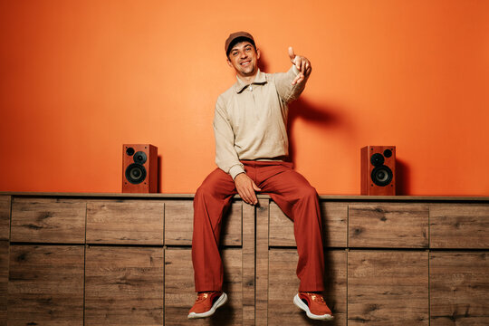 Smiling man dancing and pointing in casual clothing near vintage speakers