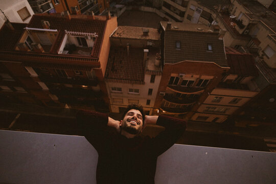Smiling man relaxing on a city rooftop at dusk