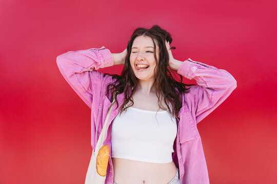 Playful woman with baguette sticking out tongue on red background