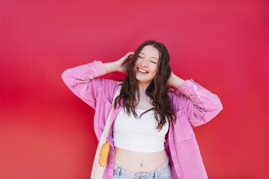 Smiling model with tote bag and baguette against red background