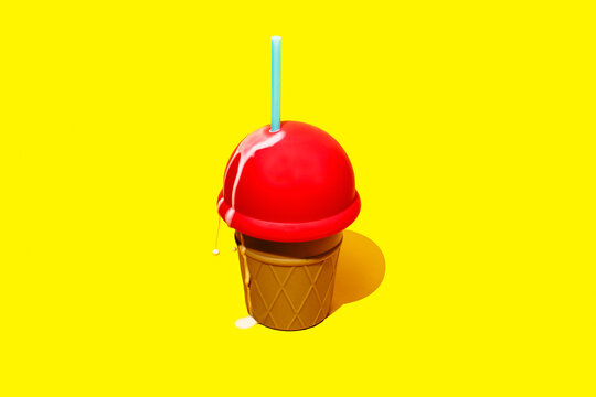 Melting ice cream shaped bottle with straw on yellow background