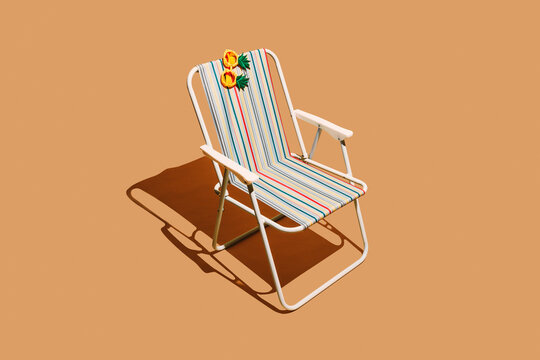 Pineapple eyewear rests on an empty striped beach chair
