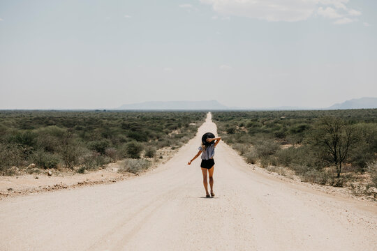 Namibia, woman walking on the road to Spitzkoppe
