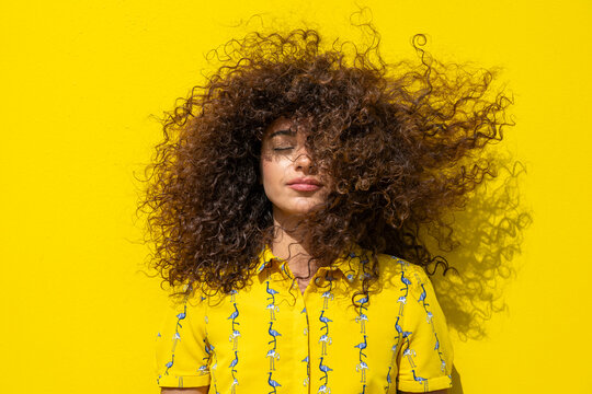 Curly hair blowing in the wind against a yellow background
