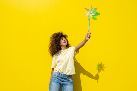 Smiling woman holding a colorful pin wheel in summer sunlight