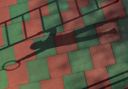 A boy casts a shadow while hanging from a playground ring