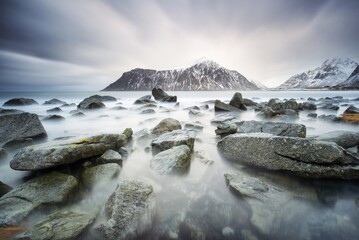 Black and white photo of rocky shoreline with mountain in background © Daniel