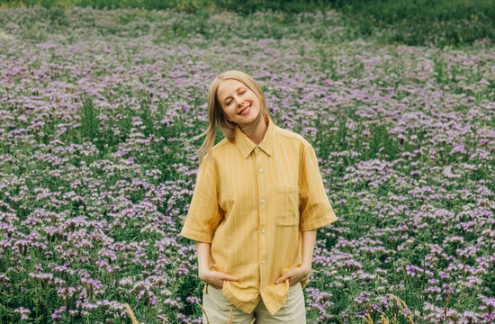 A smiling woman relaxes in a summer meadow with phacelia