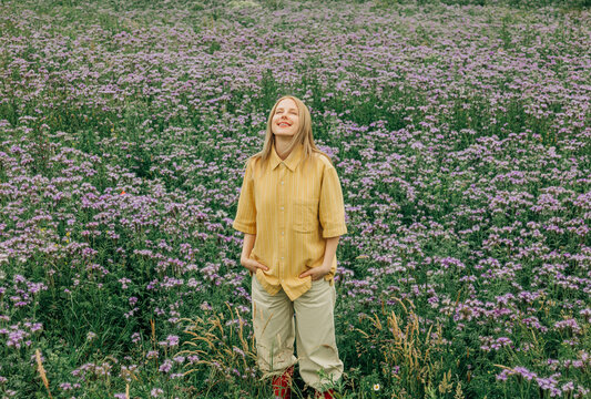 Smiling woman enjoys nature in a blooming summer phacelia meadow