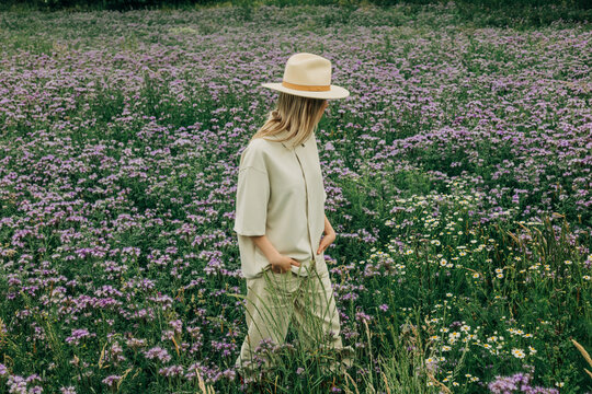 Woman relaxes in a summer meadow with purple phacelia flowers