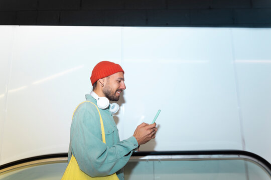 Smiling man checks his smartphone on an escalator in Barcelona