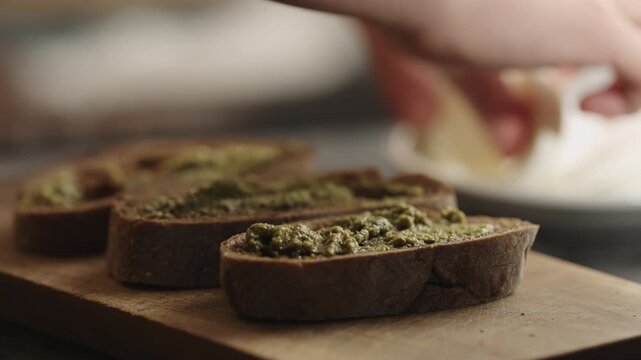 man spread pesto sauce on bread to make sandwich