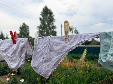 Children's and women's panties dry on a clothesline in the yard. Underwear dries outside in hot weather in the summer