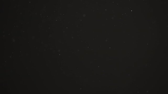 Floating dust particles over dark background with shallow focus
