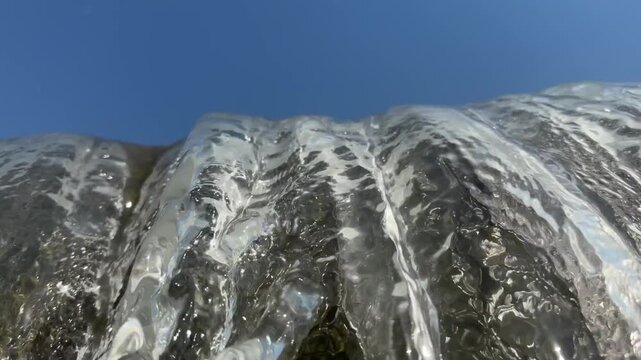 Artificial concrete check dam directs water into churning, frothy river stream lined with green trees