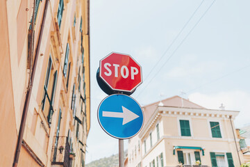 Fototapeta premium Stop sign and directional arrow guide pedestrians in a charming city street adorned with colorful buildings