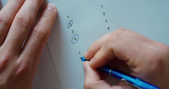 Top view of hands using a blue pen to circle a number on a sheet of paper. Concept of marking, selection, education, planning, and organization.