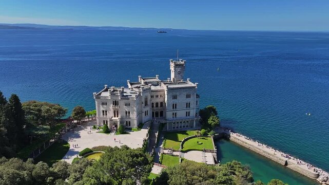 Trieste, Italy - 4K Flying around of the beautiful Miramare Castle (Castello di Miramare) by the Gulf of Trieste on a sunny summer day with blue sky and sea water