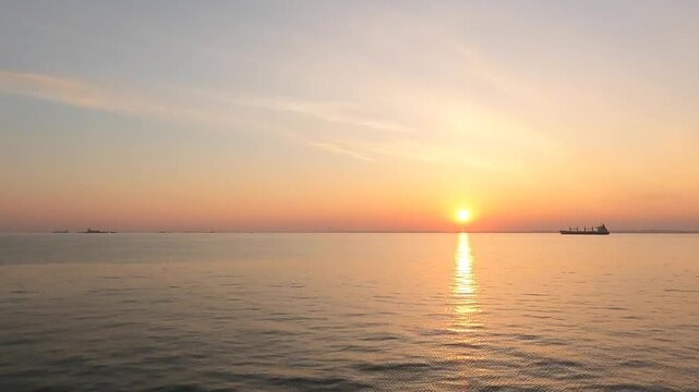 Stunning dawn video clip featuring a bright sun road next to a commercial vessel on a tranquil horizon