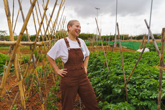 A smiling female farmer stands in an organic urban garden