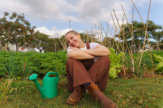 A happy woman enjoys gardening in an organic urban community garden