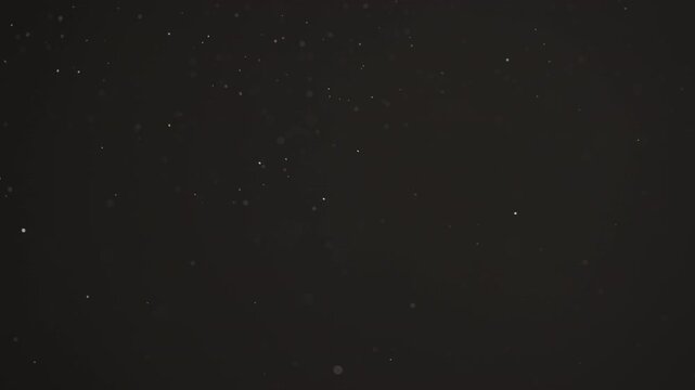 Floating dust particles over dark background with shallow focus