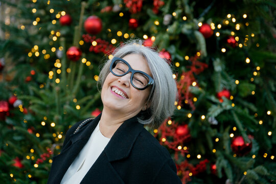 Smiling woman enjoying Christmas by a decorated tree