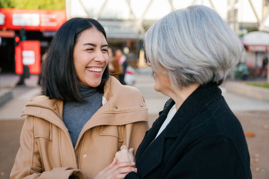 Mother and daughter smiling together outdoors in the city