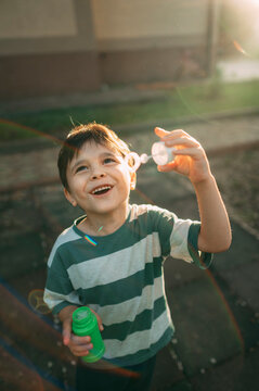 A happy boy blows a soap bubble in the park during summer