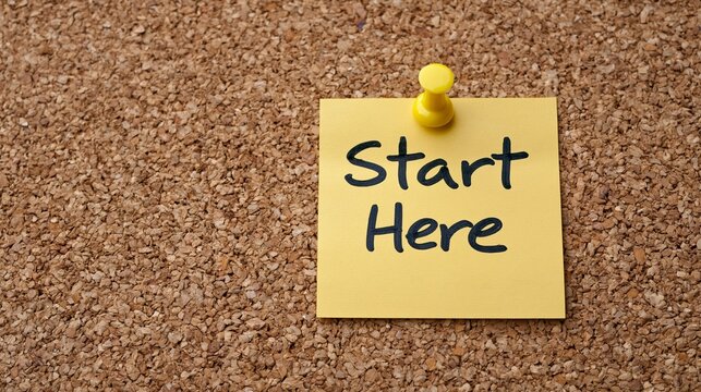 Small square note with Start Here text pinned to a corkboard.
