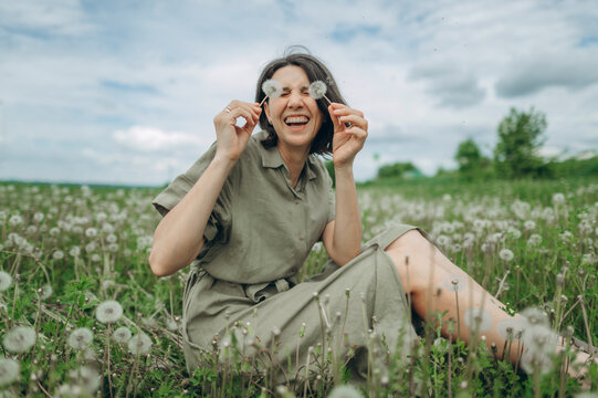 Womannjoying peace and laughing in a summer dandelion field