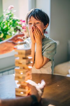 Family playing wooden block tower game indoors with excitement