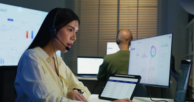 Attractive woman working at a desk as a financial advisor. She uses a headset and computer to consult with clients, offering expert advice in a professional corporate office setting.