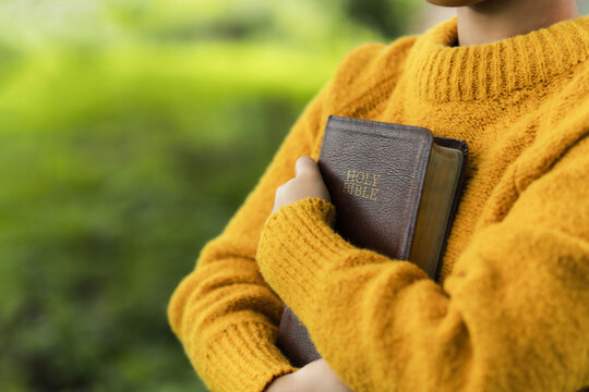The young woman is praying while holding a Bible. Concepts of offering prayer and praise to God. prayer and praise with the Bible.