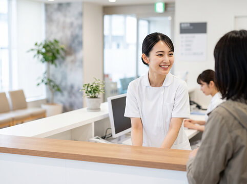 病院の受付窓口で患者に親切に案内をする笑顔の医療事務女性