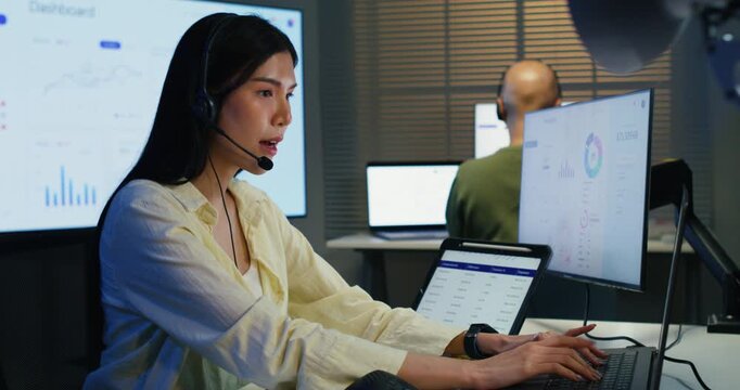 Professional woman sitting at a computer desk providing technology consulting. She uses a headset for clear communication and client support within a modern corporate workplace. 