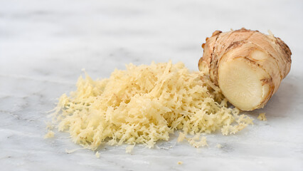 Fototapeta premium Freshly grated ginger and whole root on white marble