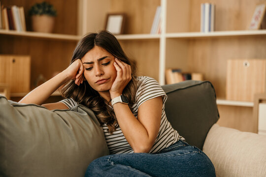 Young woman feeling sad and tired on sofa