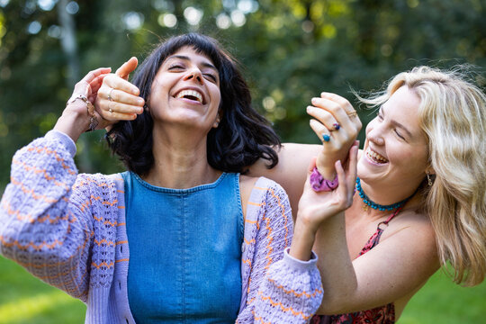 Happy female friends laughing and playing together in a summer park
