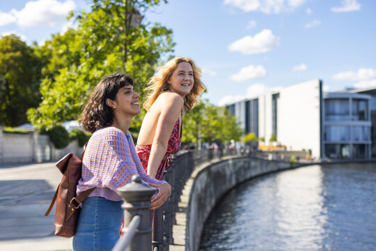 Happy female friends enjoy a sunny riverside walk in Berlin
