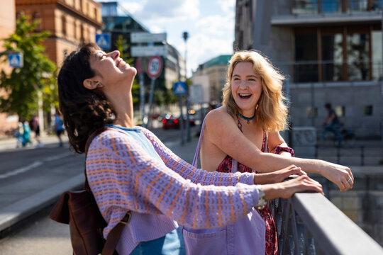 A woman and her friend share a laugh on a bridge in Berlin