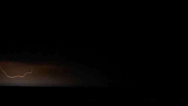 ​4K UHD night thunderstorm with dramatic lightning strikes and bright flashes illuminating storm clouds on a dark horizon.