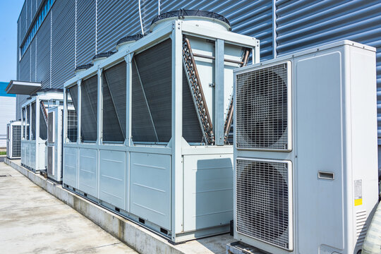 Industrial air conditioning units lined up outside a modern building facade