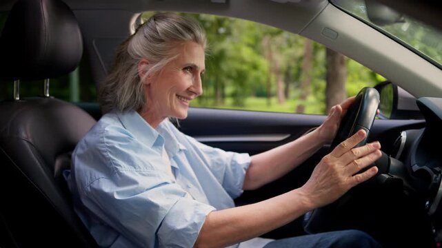 Active carefree Caucasian senior old woman turn on music dashboard in car luxury auto retired senior female driver granny mature lady listening musical audio dancing in rental automobile listen song