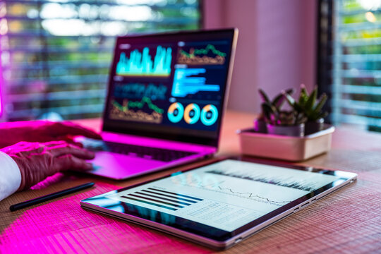 Man analyzes financial data on laptop and tablet in the office