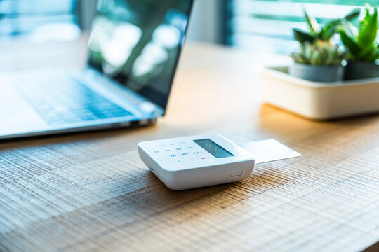 Credit card reader and laptop on a wooden desk in an office
