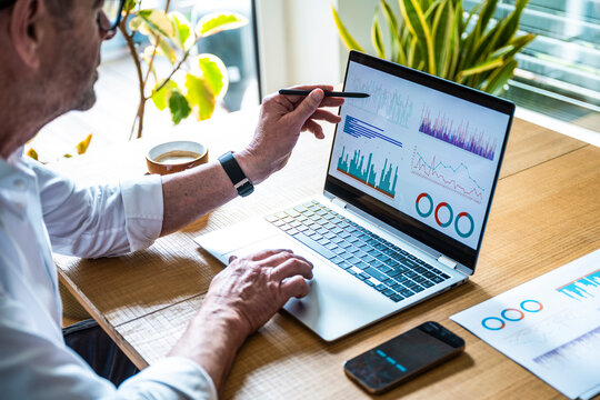 A man points at financial data on a notebook screen in the office