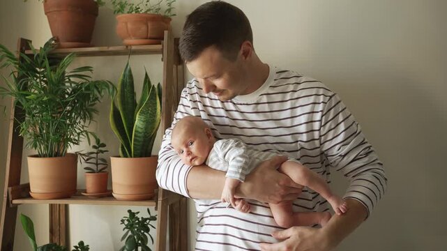 Tender moment of a loving father gently holding and cradling his newborn baby in his arms, showcasing the beautiful bond between a parent and child and the joy of fatherhood at home