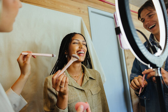 Friends enjoying makeup application during a fun creative photo session