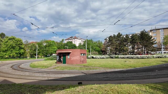 Prague, Czech Republic - April 27, 2026 - Urban tramway tracks curve past a small brick building on a sunny day